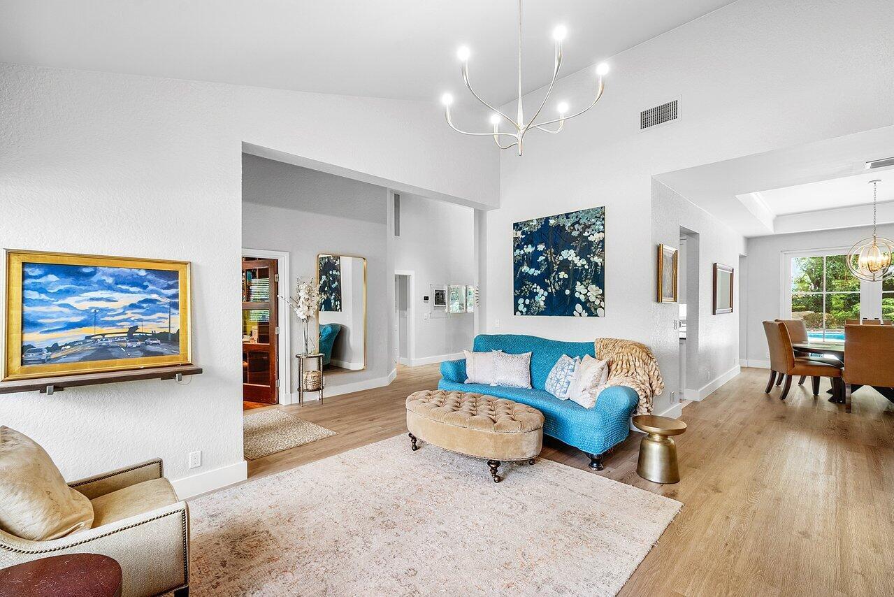 A bright living room features a blue sofa, a beige ottoman, and light wood flooring — 3010 Hampton Circle, Boca Raton FL 33434, BOCA RATON, FL