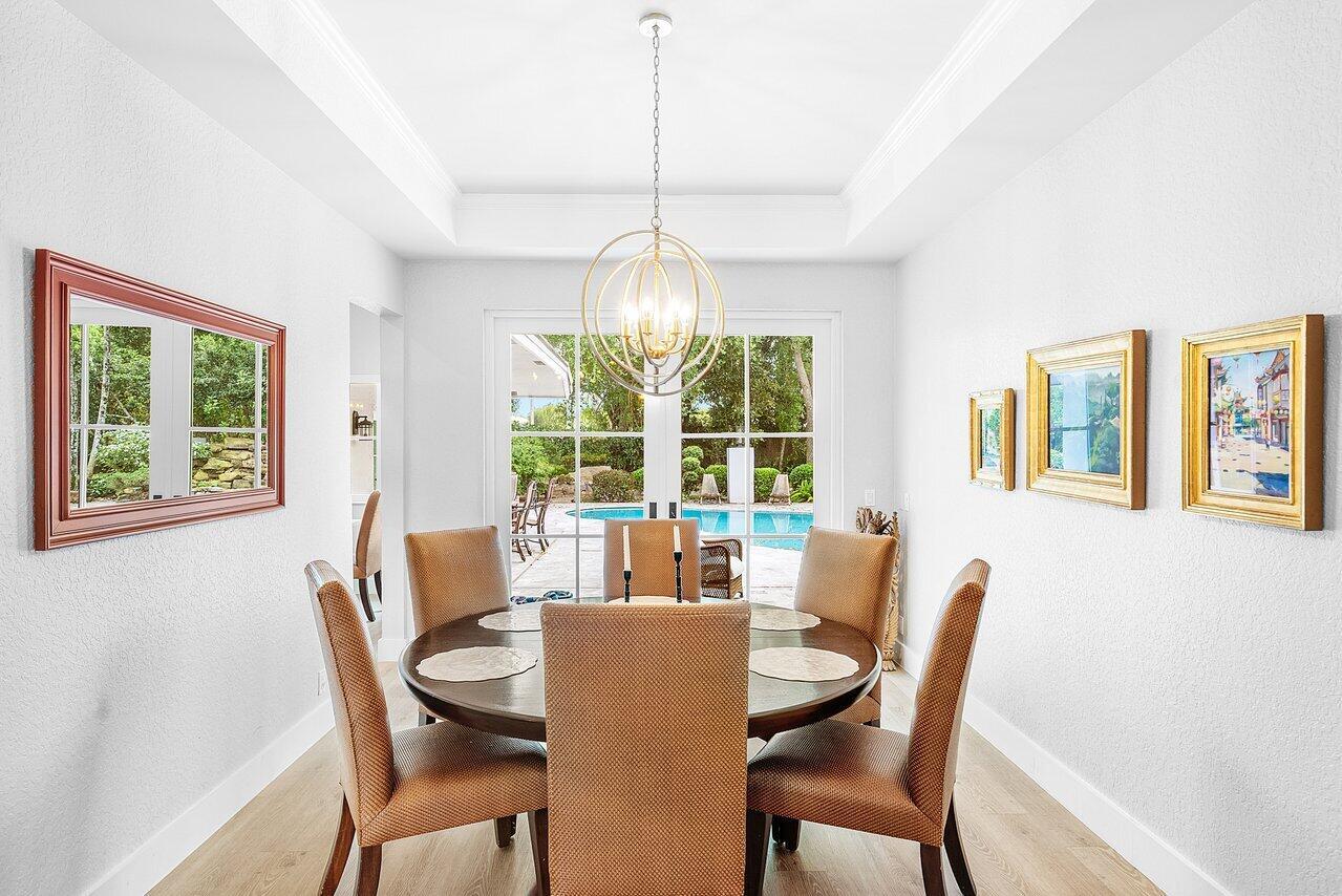 A dining room features a round table, six chairs, a chandelier, and a pool view — 3010 Hampton Circle, Boca Raton FL 33434, BOCA RATON, FL