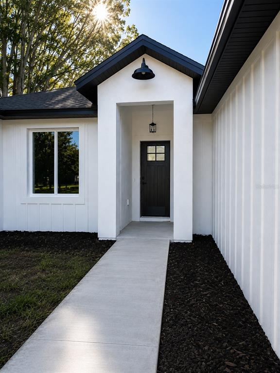 A modern white house exterior features a black front door, dark roof, and concrete walkway — 14451 SE 43RD TERRACE, SUMMERFIELD, FL