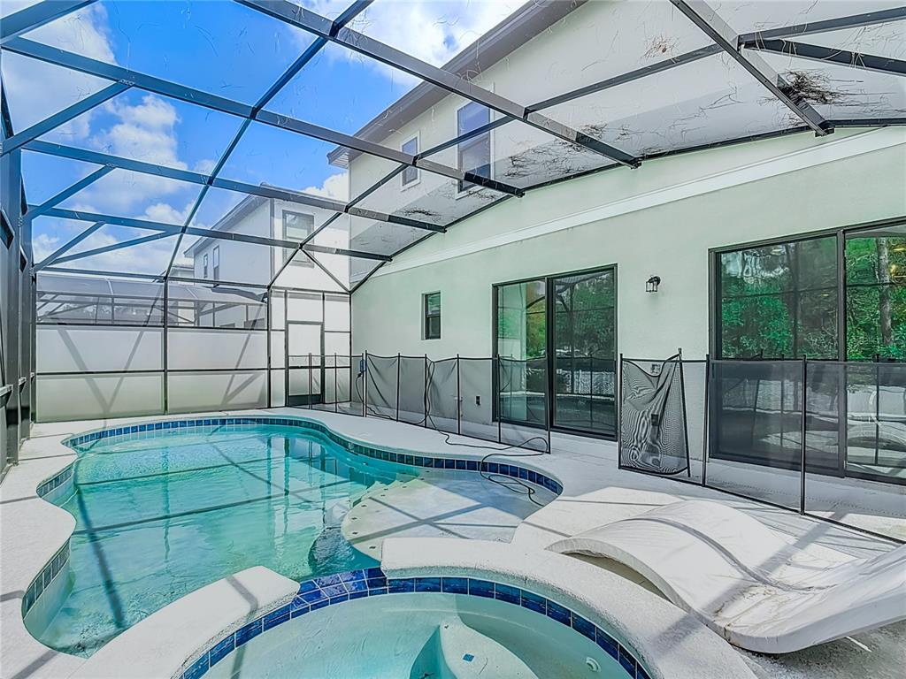 A screened-in patio features a swimming pool, a hot tub, and a removable safety fence — 1326 BUTTERFLY ORCHID ROAD, DAVENPORT, FL