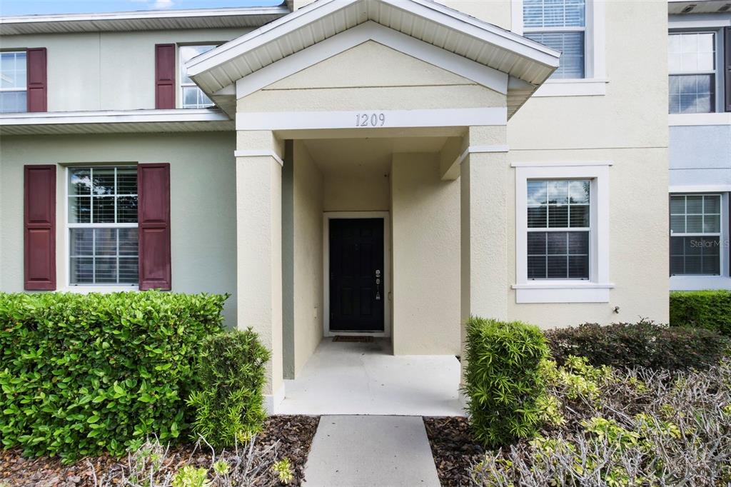 The exterior of a two-story residential building features a covered entryway with a black door — 1209 SEBURN ROAD, APOPKA, FL