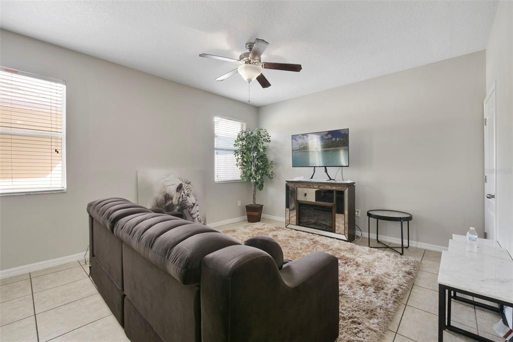 A living room features a dark sofa, a mirrored media console, and a shag rug — 1209 SEBURN ROAD, APOPKA, FL