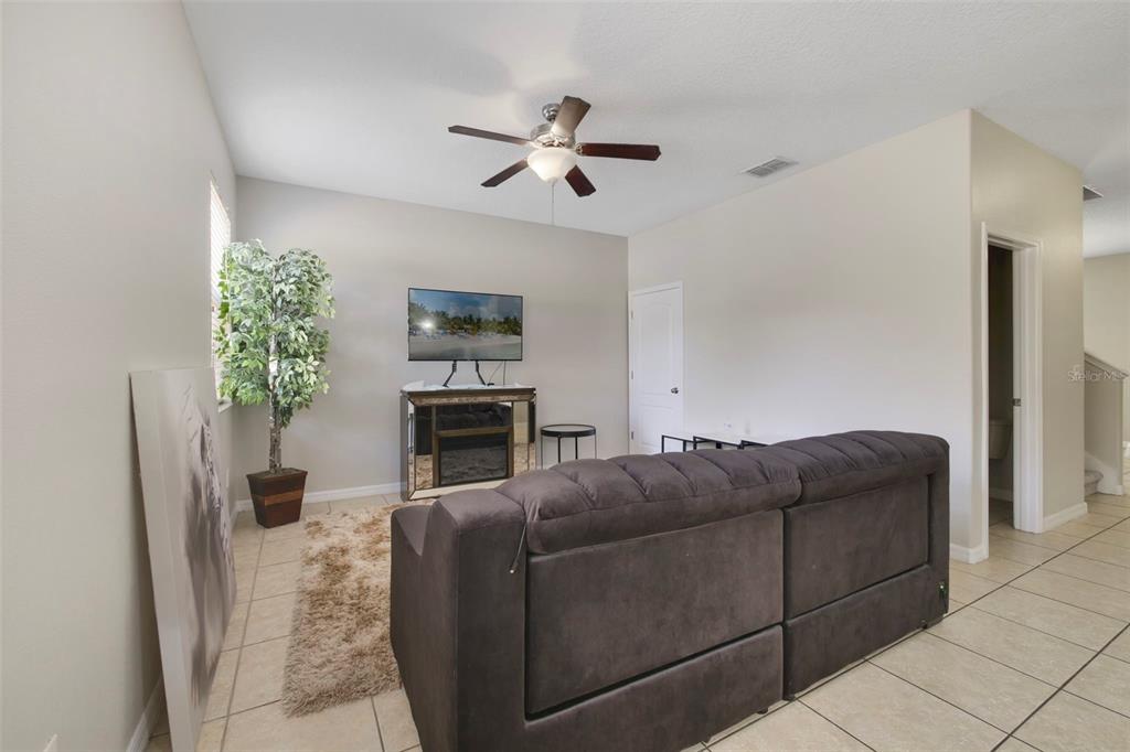 A living room features a dark sofa, a mirrored media console, and a ceiling fan — 1209 SEBURN ROAD, APOPKA, FL