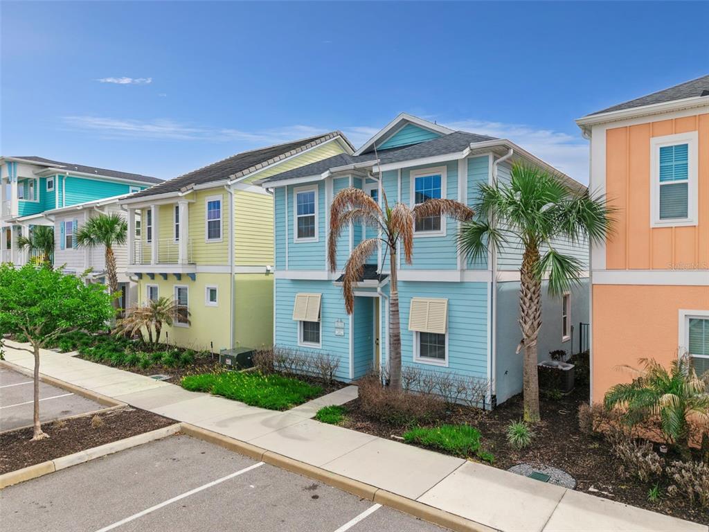 A row of colorful, two-story suburban houses with siding and palm trees in front — 8019 KNEE DEEP ROAD, KISSIMMEE, FL