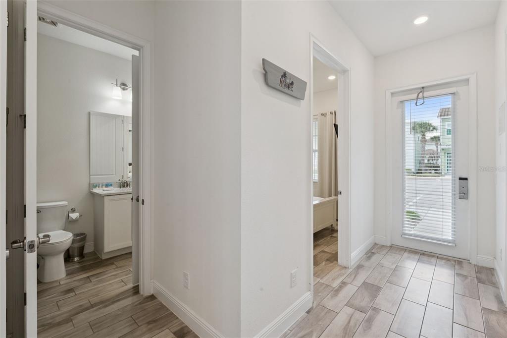 A hallway with tile flooring leads to a bathroom, a bedroom, and an exterior door — 8019 KNEE DEEP ROAD, KISSIMMEE, FL