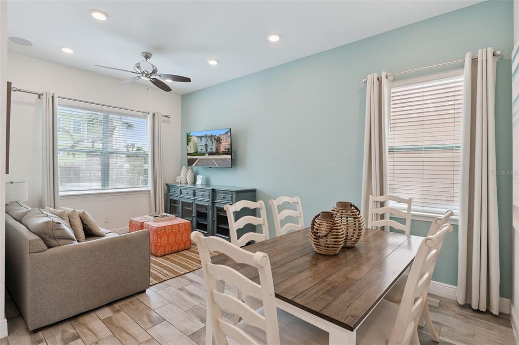 A living and dining area features light blue walls, wood-look tile flooring, and a ceiling fan — 8019 KNEE DEEP ROAD, KISSIMMEE, FL