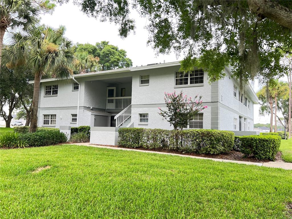 A two-story apartment building with light gray stucco walls and a central staircase — 572 FAIRWAYS LANE UNIT N204, OCALA, FL