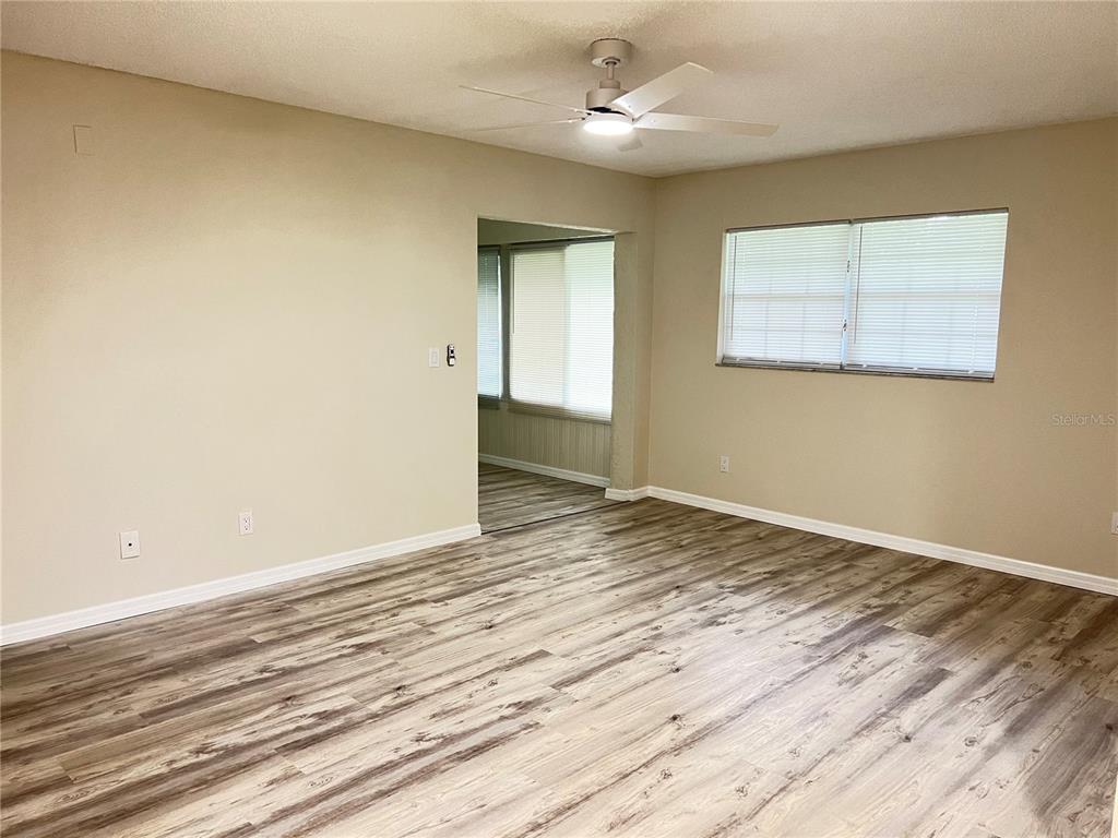 A living room with light-colored walls, wood-look flooring, and a ceiling fan — 572 FAIRWAYS LANE UNIT N204, OCALA, FL