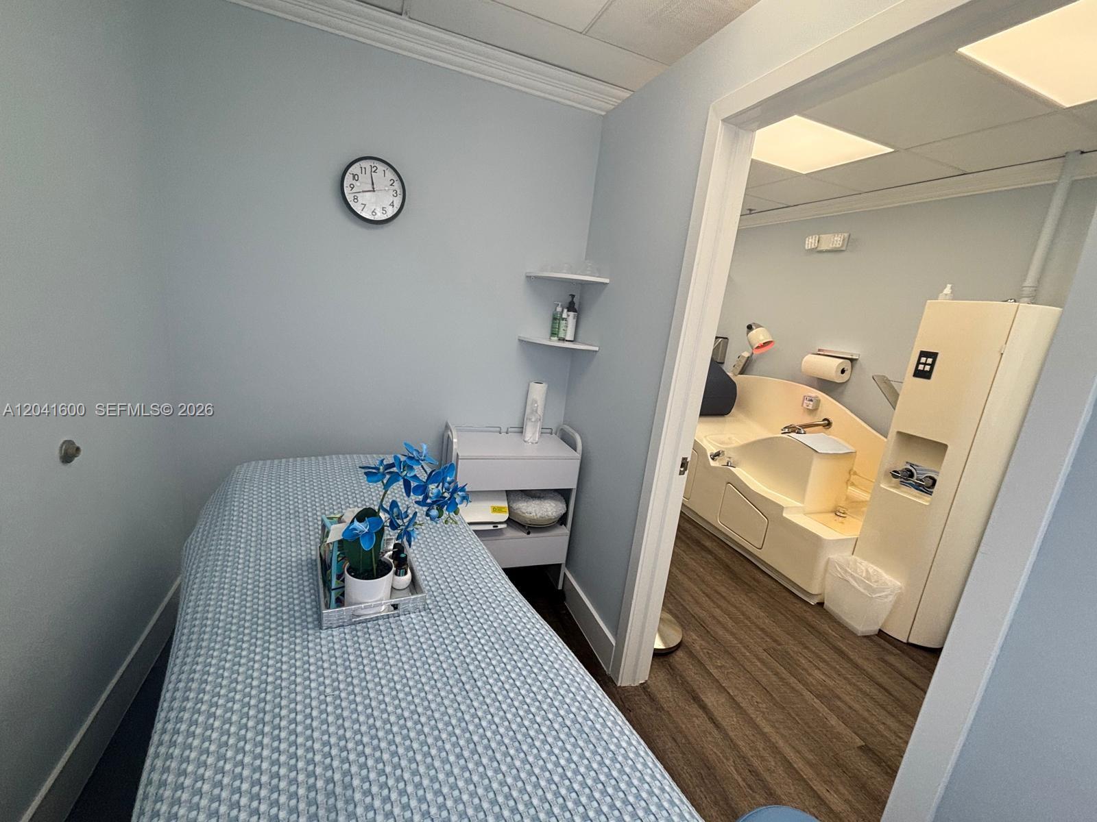 A treatment room with a massage table leads into a separate room with a tub — WESTON, FL