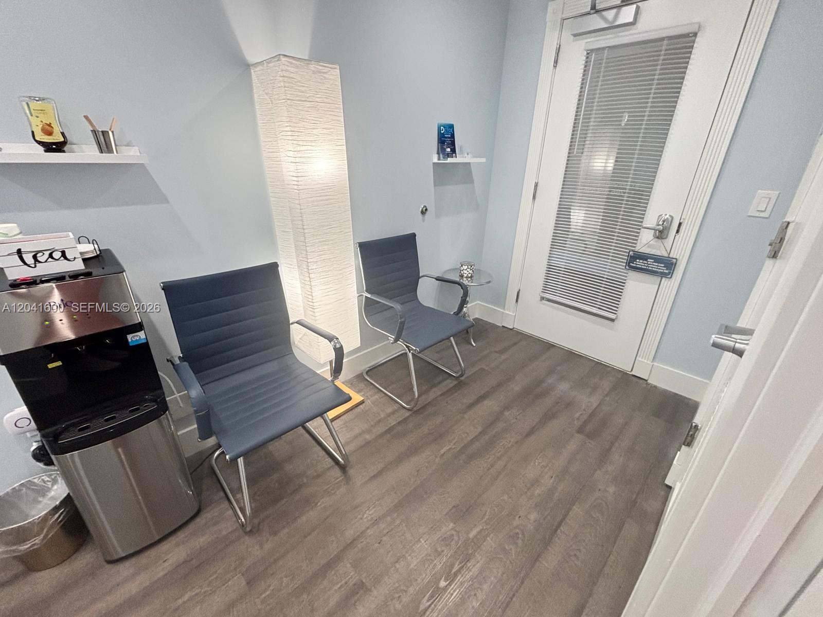 A waiting room features two blue chairs, a floor lamp, and a water cooler — WESTON, FL