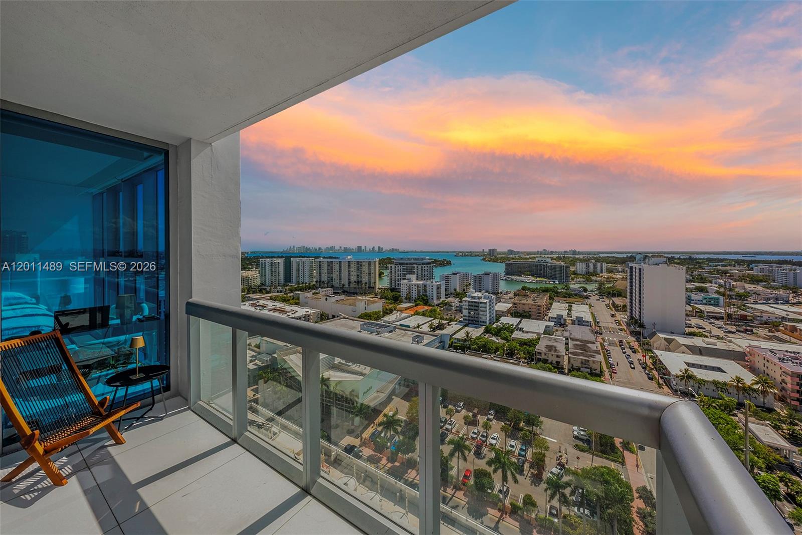 A high-rise balcony overlooks a city skyline and bay under a sunset sky — 6899 Collins Ave # 2004, Miami Beach FL 33141, MIAMI BEACH, FL