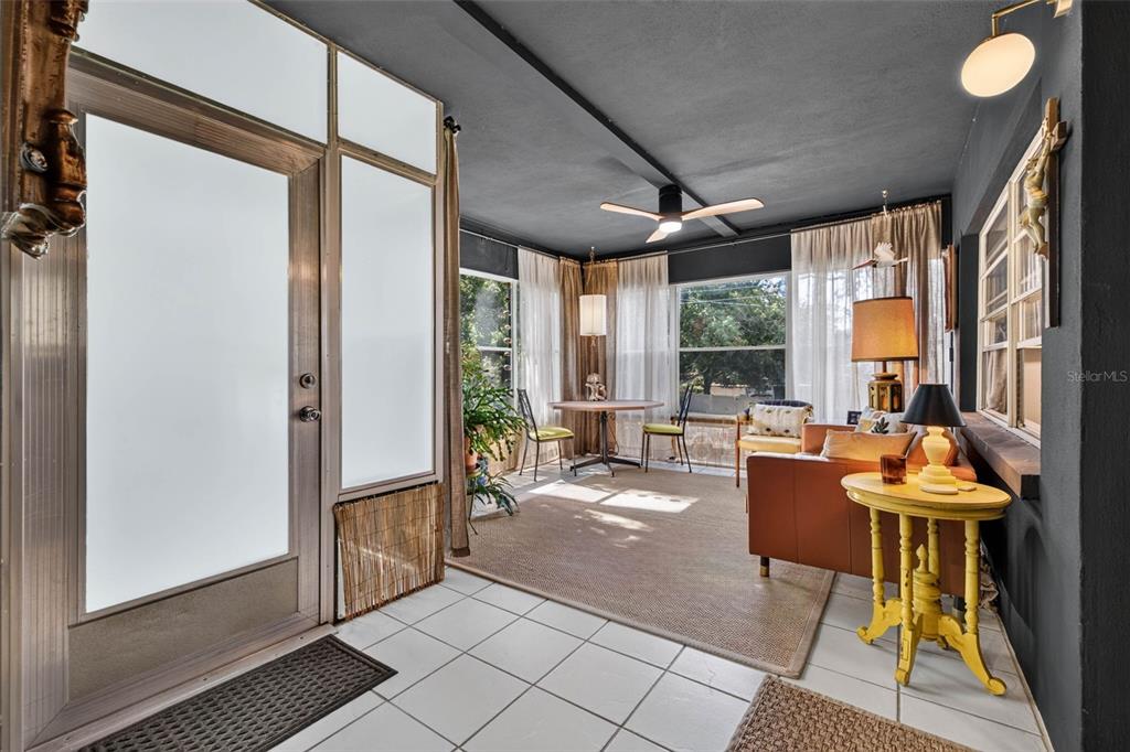 A sunroom features a dark ceiling, white tile flooring, a dining area, and a sofa — 4819 8TH AVENUE N UNIT 201, ST PETERSBURG, FL
