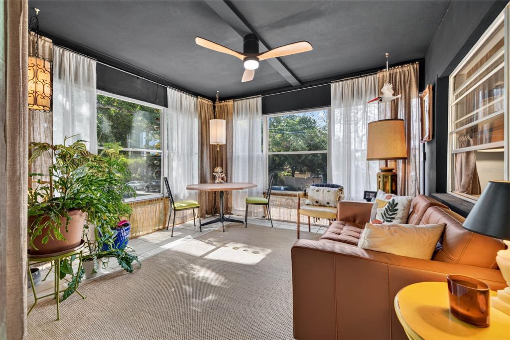 A sunroom features a dark ceiling, a ceiling fan, large windows, and a leather sofa — 4819 8TH AVENUE N UNIT 201, ST PETERSBURG, FL