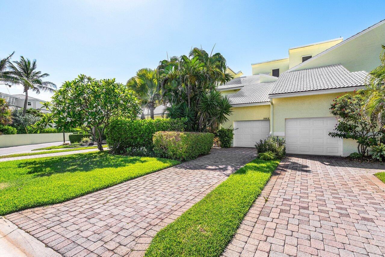 A two-story house with a paved driveway and two garage doors sits behind lush landscaping — 5109 N Ocean E Boulevard, Ocean Ridge FL 33435, OCEAN RIDGE, FL