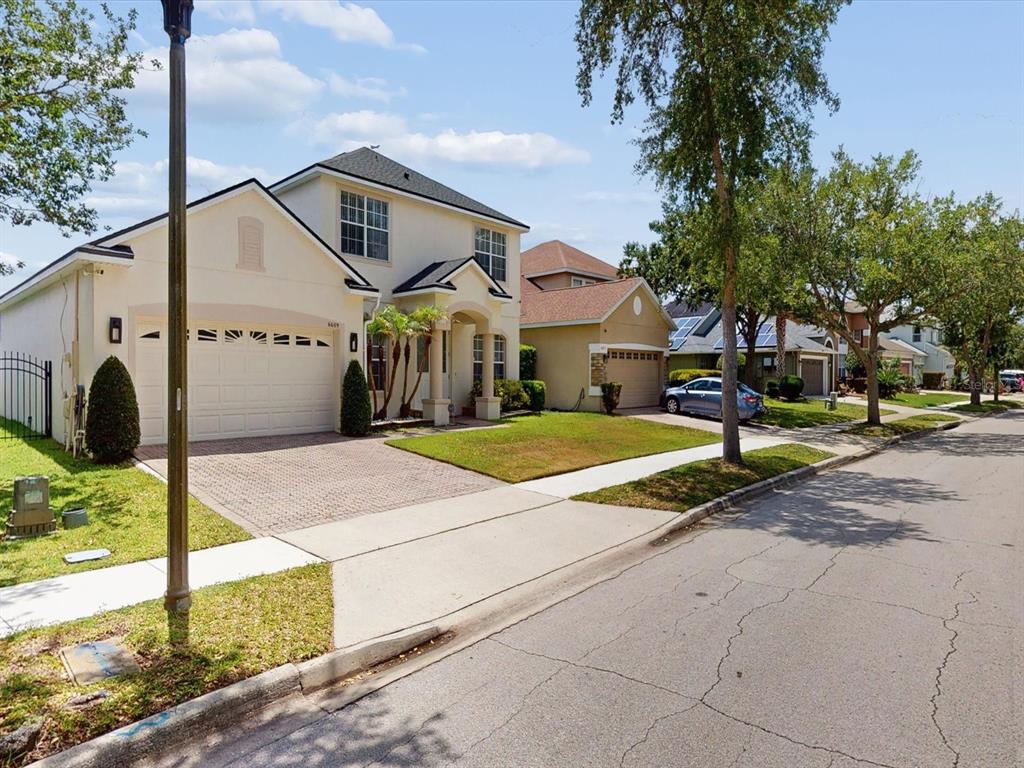 A two-story suburban house with a paved driveway and a front lawn on a street — 6609 LAKE PEMBROKE PLACE, ORLANDO, FL