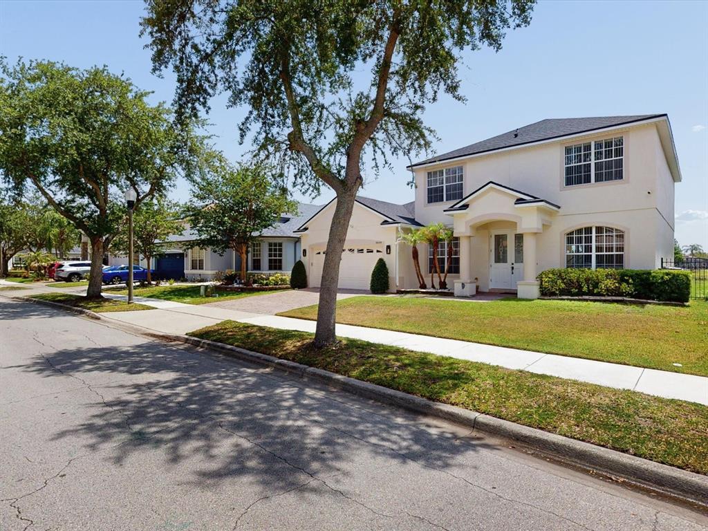 A two-story suburban house with a light-colored exterior, a two-car garage, and a front lawn — 6609 LAKE PEMBROKE PLACE, ORLANDO, FL