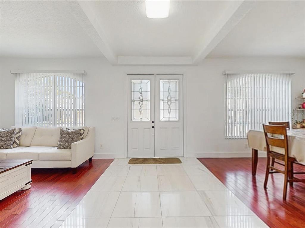 A living and dining area features white tile flooring, hardwood floors, and a double front door — 6609 LAKE PEMBROKE PLACE, ORLANDO, FL