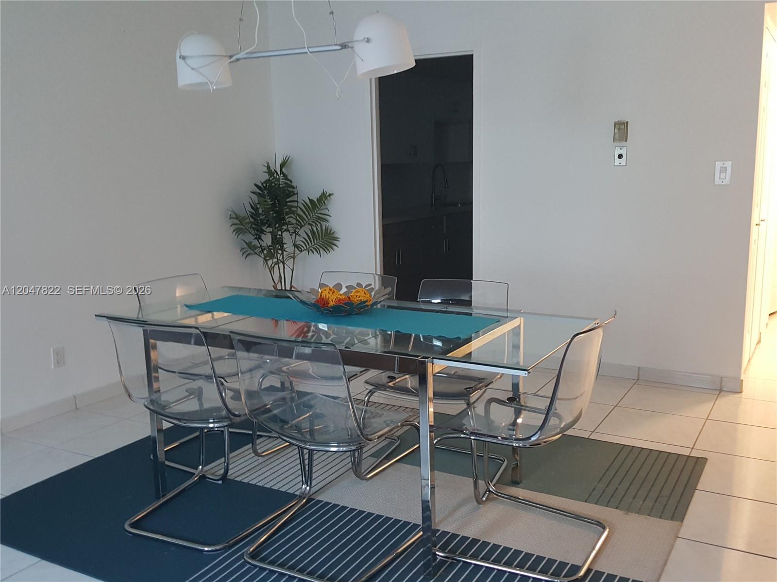 A dining room features a glass table with clear chairs on a striped rug — 5401 Collins Ave # 311, Miami Beach FL 33140, MIAMI BEACH, FL
