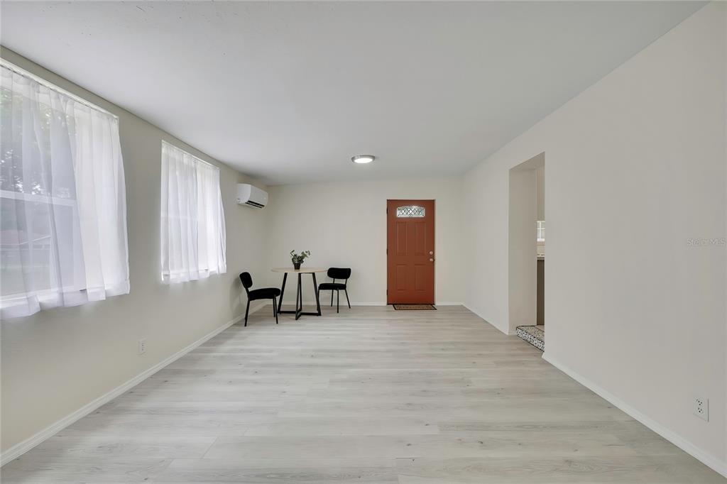 A bright, minimalist room features light wood-look flooring, white walls, two windows, and a dining set — 5175 E LIVE OAK LANE, INVERNESS, FL