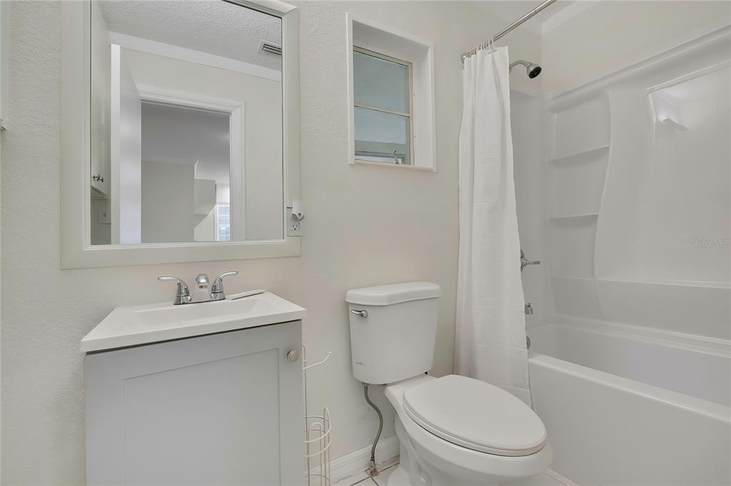 A bathroom features a gray vanity, a white toilet, and a shower-tub combination — 5175 E LIVE OAK LANE, INVERNESS, FL