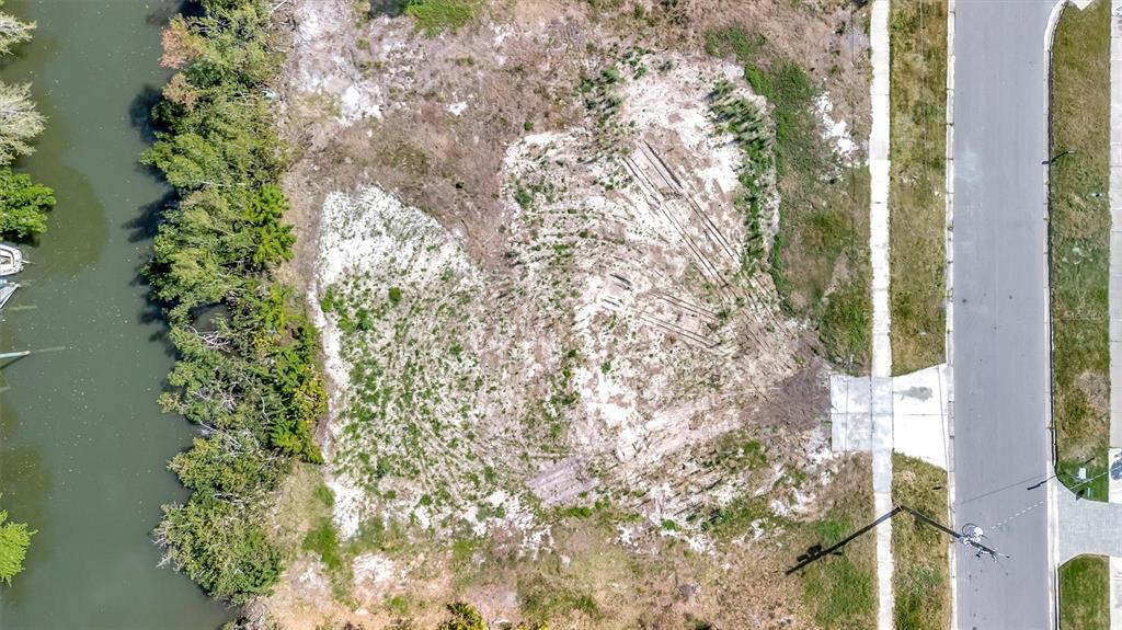 An aerial view shows a vacant, sandy lot situated between a road and a waterway — 2618 S DUNDEE STREET UNIT PARCEL A, TAMPA, FL