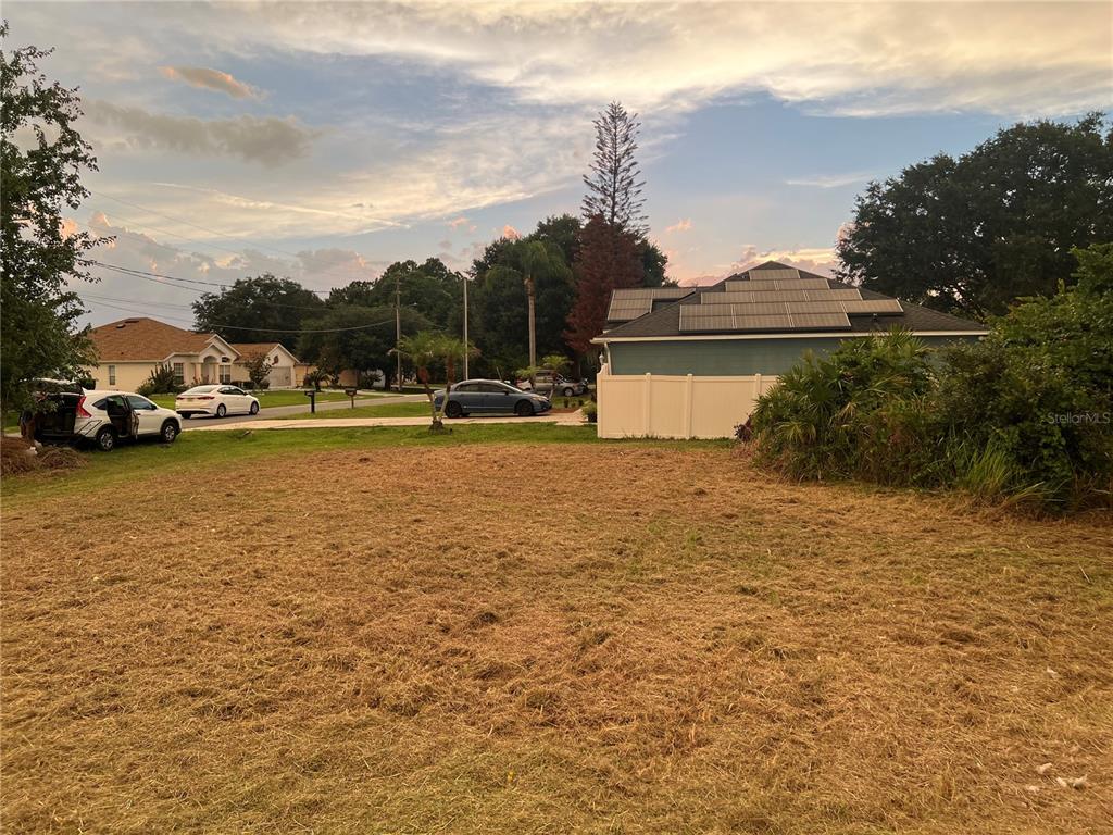 A large, cleared grassy lot sits in front of a house with solar panels — 808 HALIFAX DRIVE, KISSIMMEE, FL