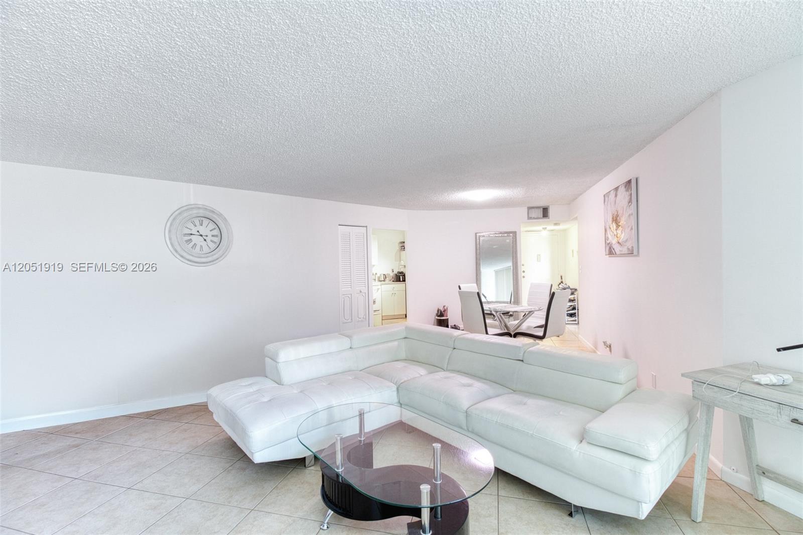 A living room features a white sectional sofa, a glass coffee table, and tile flooring — 800 Parkview Dr # 311, Hallandale Beach FL 33009, HALLANDALE BEACH, FL