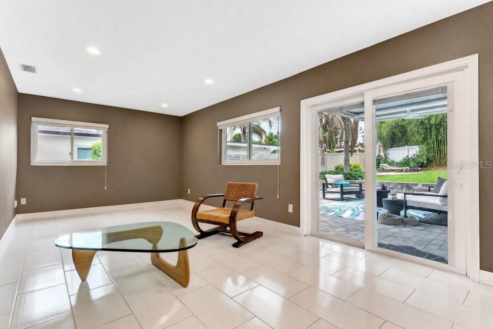 A living room with brown walls, white tile flooring, a glass coffee table, and sliding doors — 514 BAKER STREET, ORLANDO, FL
