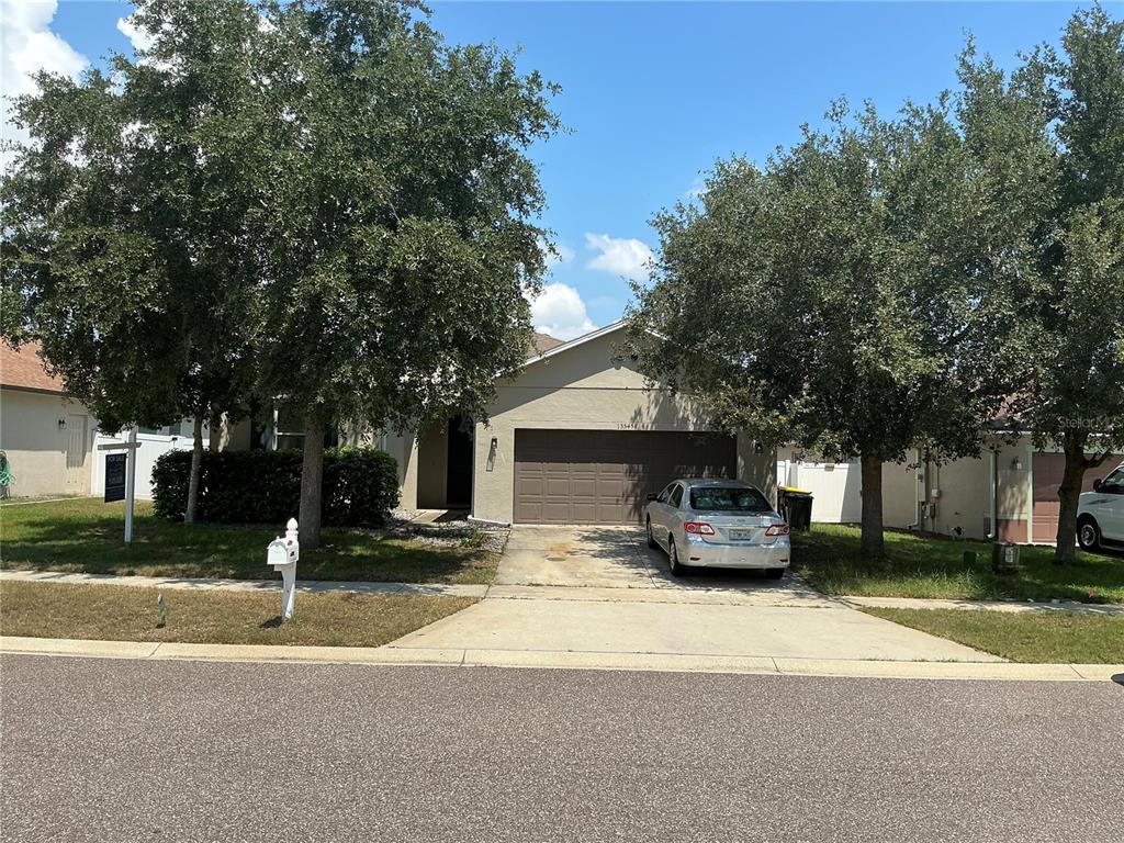 A single-story house with a two-car garage and two large trees in the front yard — 13545 LARANJA STREET, CLERMONT, FL