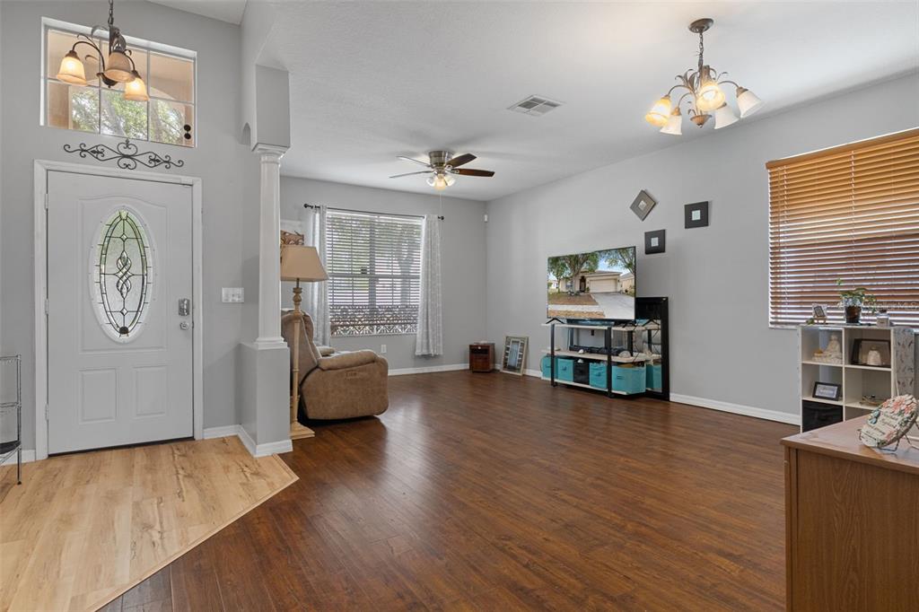 A living room features wood-look flooring, a ceiling fan, a television stand, and an entryway — 8483 PINETOP RIDGE LANE, BROOKSVILLE, FL