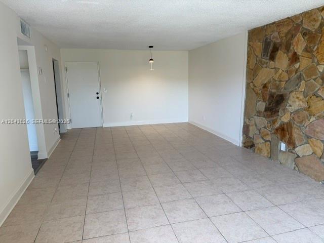 An empty room features light-colored floor tiles and a prominent stone accent wall — 8405 NW 8th St # 303, Miami FL 33126, MIAMI, FL