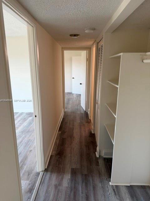 A hallway with wood-look flooring leads to a doorway, featuring open shelving on the right — 8405 NW 8th St # 303, Miami FL 33126, MIAMI, FL