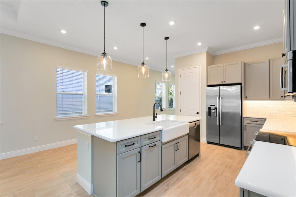 A kitchen features a gray island with a farmhouse sink, stainless appliances, and light flooring — 8828 SPERRY STREET, ORLANDO, FL
