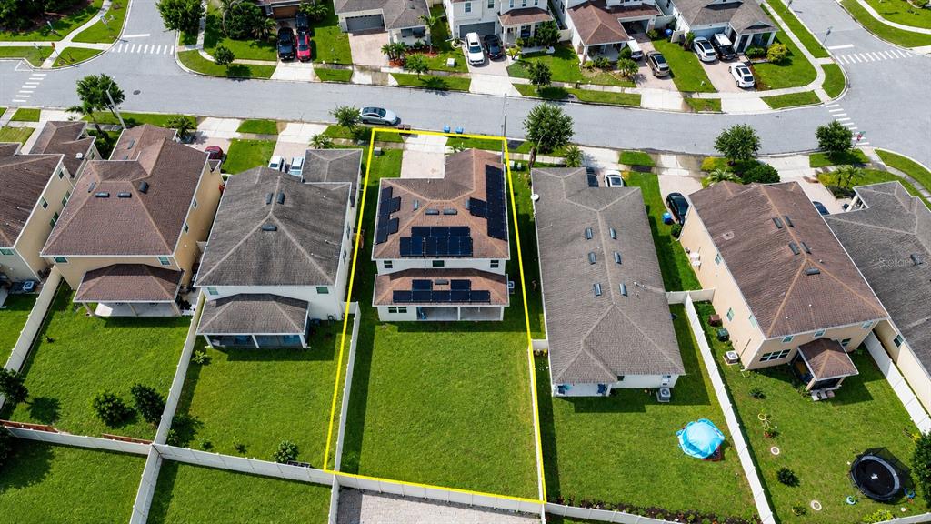 An aerial view shows a two-story house with solar panels on the roof and a backyard — 3430 CANVAS STREET, KISSIMMEE, FL