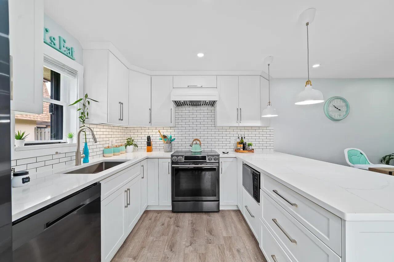 A modern kitchen features white cabinets, a subway tile backsplash, and a large quartz island — 3132 SW 20th Terrace # 12b, Delray Beach FL 33445, DELRAY BEACH, FL