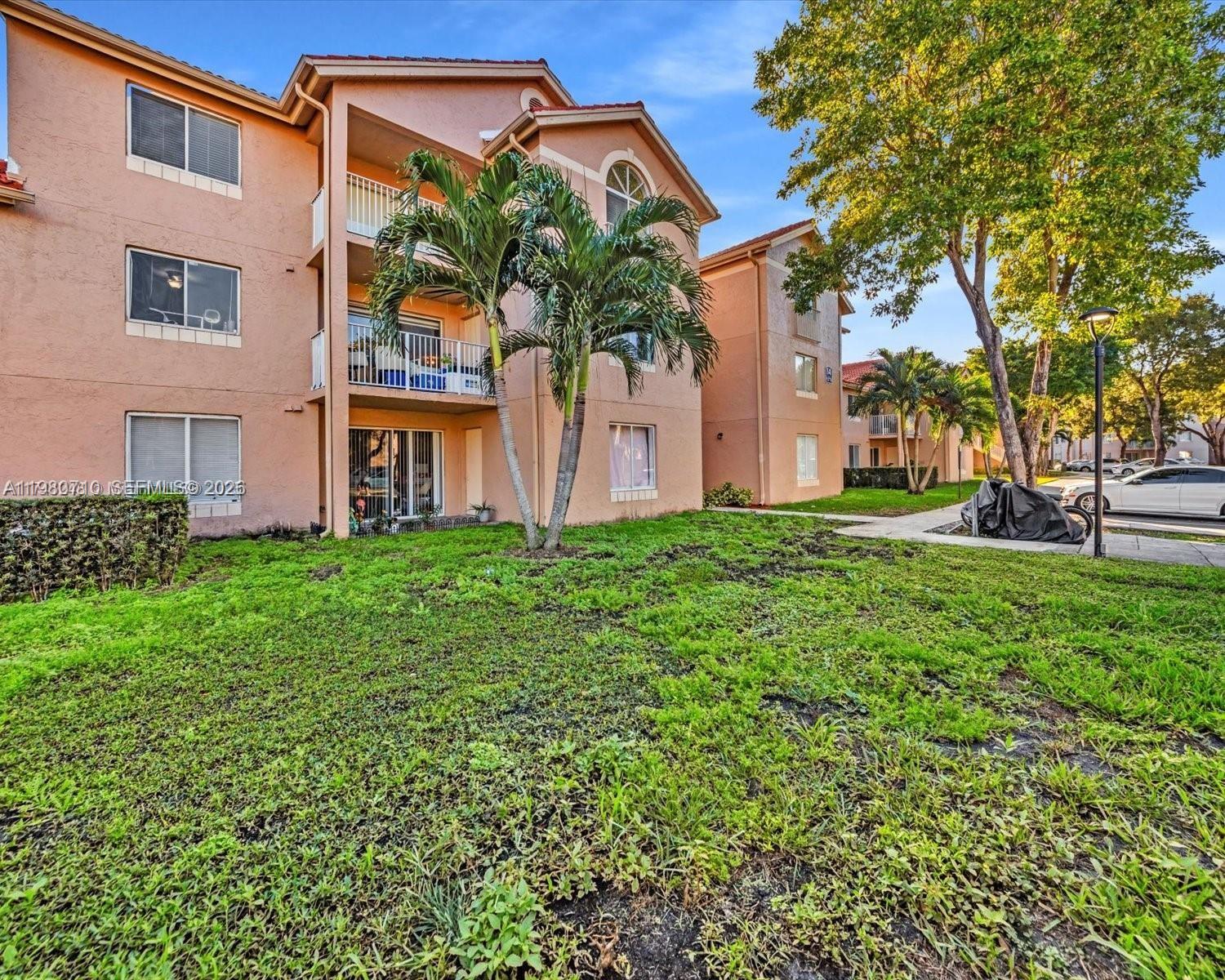 A multi-story apartment building with a tiled roof, exterior staircases, and a parking lot — 15770 SW 106th Ter # 303, Miami FL 33196, MIAMI, FL