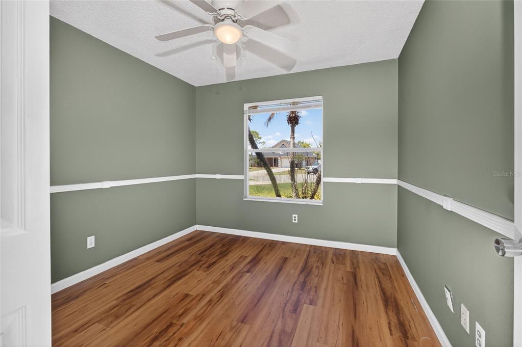 An empty room features sage green walls, white chair rail molding, and wood-look flooring — 861 BLACKGUM COURT, ORLANDO, FL