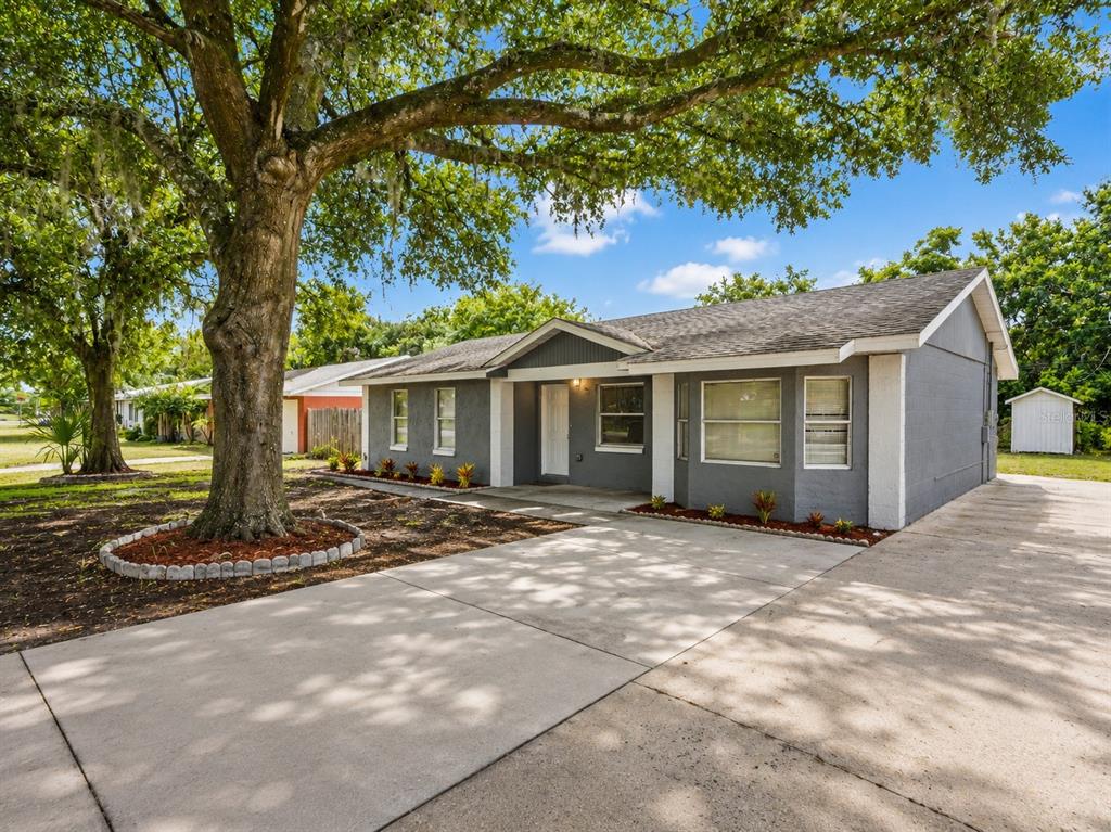 A gray single-story house with a concrete driveway and a large tree in the yard — 4042 HOMESTEAD DRIVE, LAKELAND, FL