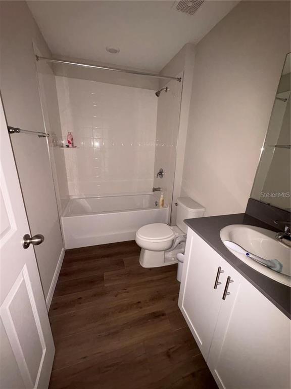 A bathroom features a white vanity, a toilet, and a shower-tub combination with wood-look flooring — 11484 BROOK EDGE AVENUE, RIVERVIEW, FL