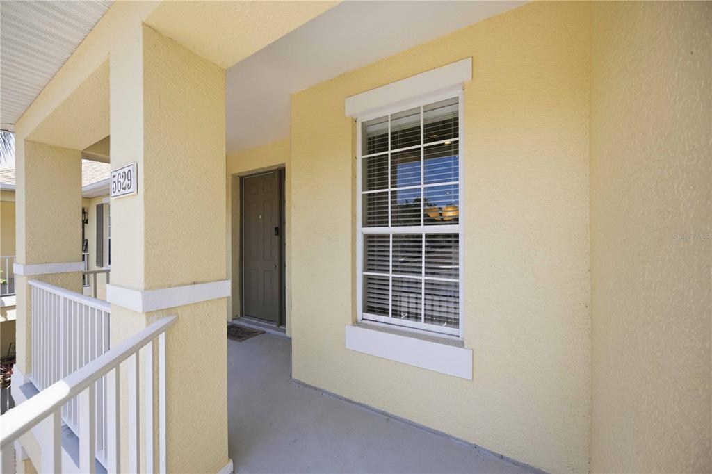 A yellow stucco exterior wall features a front door, a window, and a house number — 5629 KEY LARGO COURT UNIT B06, BRADENTON, FL