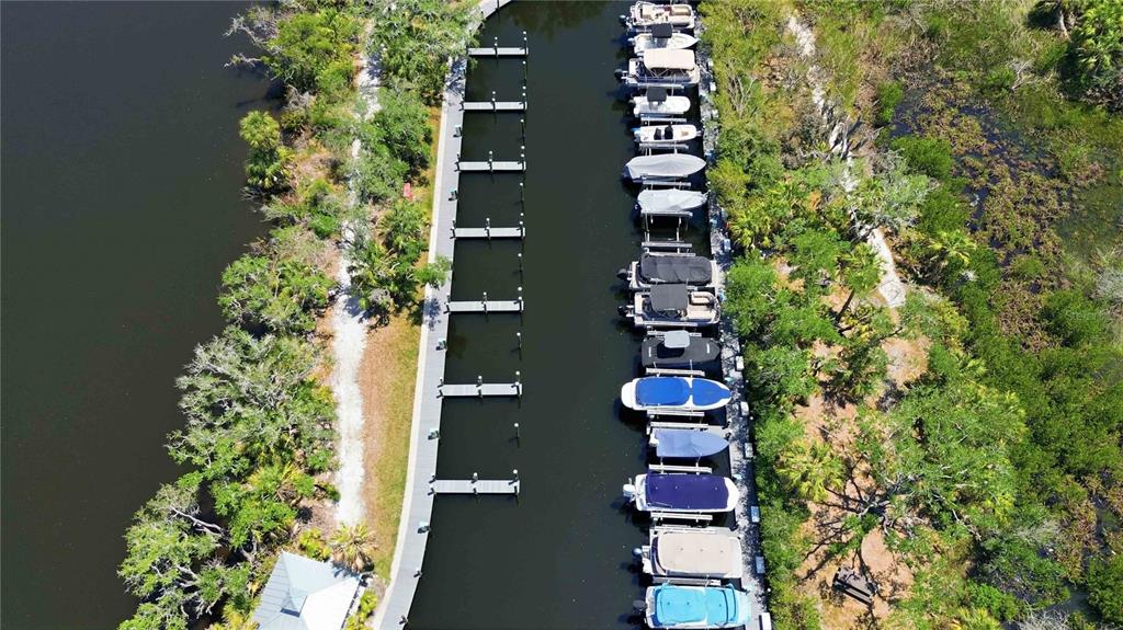 An aerial view shows a boat dock with several moored vessels along a narrow waterway — 5629 KEY LARGO COURT UNIT B06, BRADENTON, FL