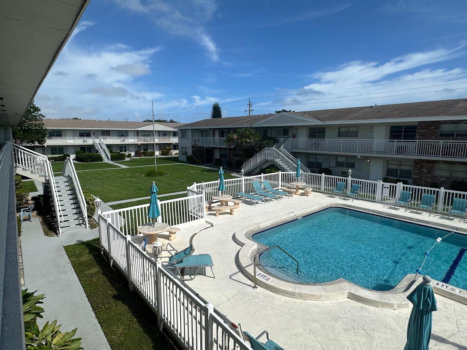An elevated view of an apartment complex courtyard featuring a swimming pool and green lawn — 3850 NE 21st Way # 41, Lighthouse Point FL 33064, LIGHTHOUSE POINT, FL
