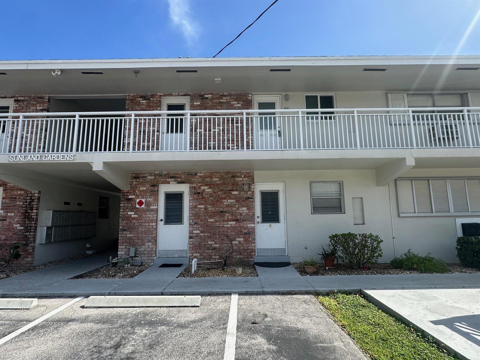 A two-story apartment building exterior features brick accents, white railings, and ground-level entry doors — 3850 NE 21st Way # 41, Lighthouse Point FL 33064, LIGHTHOUSE POINT, FL