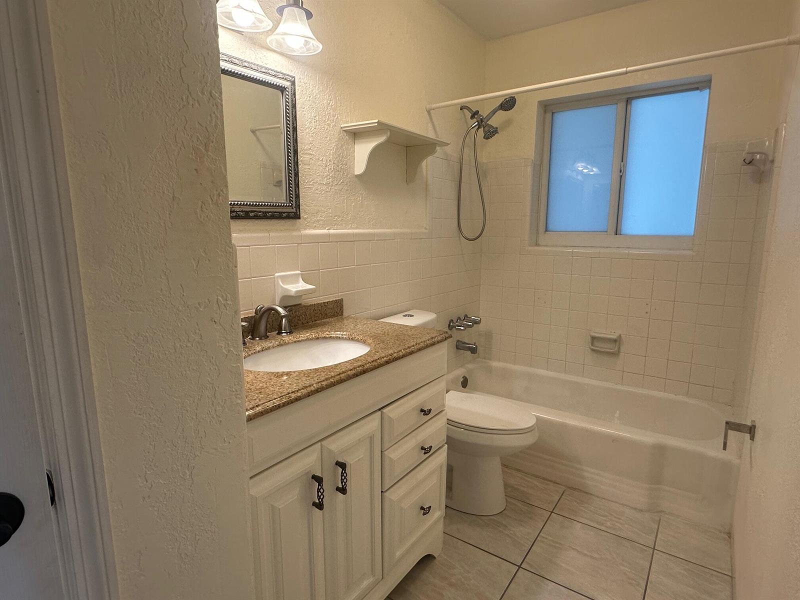 A bathroom features a white vanity with a granite countertop, a toilet, and a tub-shower — 3850 NE 21st Way # 41, Lighthouse Point FL 33064, LIGHTHOUSE POINT, FL