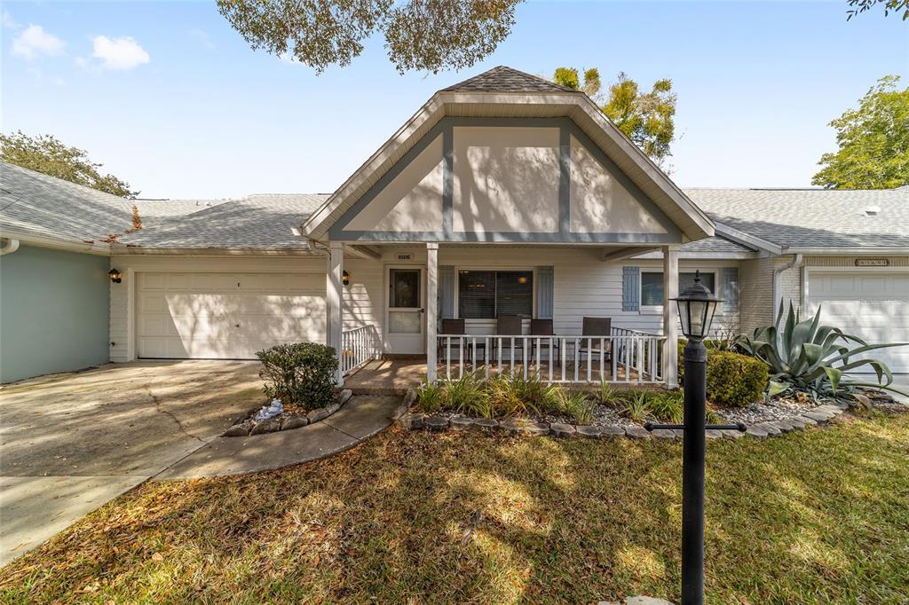 A single-story house with a white exterior, a front porch, and an attached garage — 8569 SW 92ND LANE UNIT E, OCALA, FL