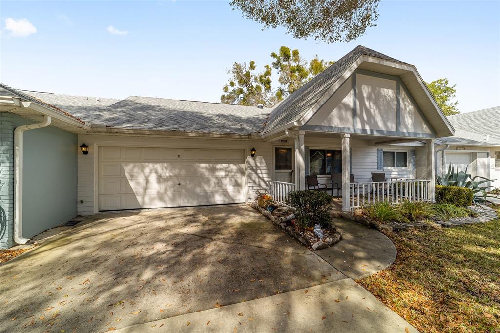 A single-story house features a white garage, a covered front porch, and a concrete driveway — 8569 SW 92ND LANE UNIT E, OCALA, FL