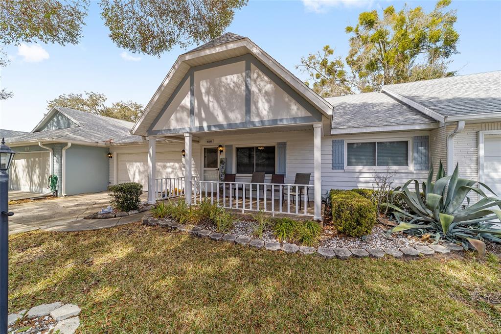 A single-story house with a covered front porch, white siding, and a large agave plant — 8569 SW 92ND LANE UNIT E, OCALA, FL