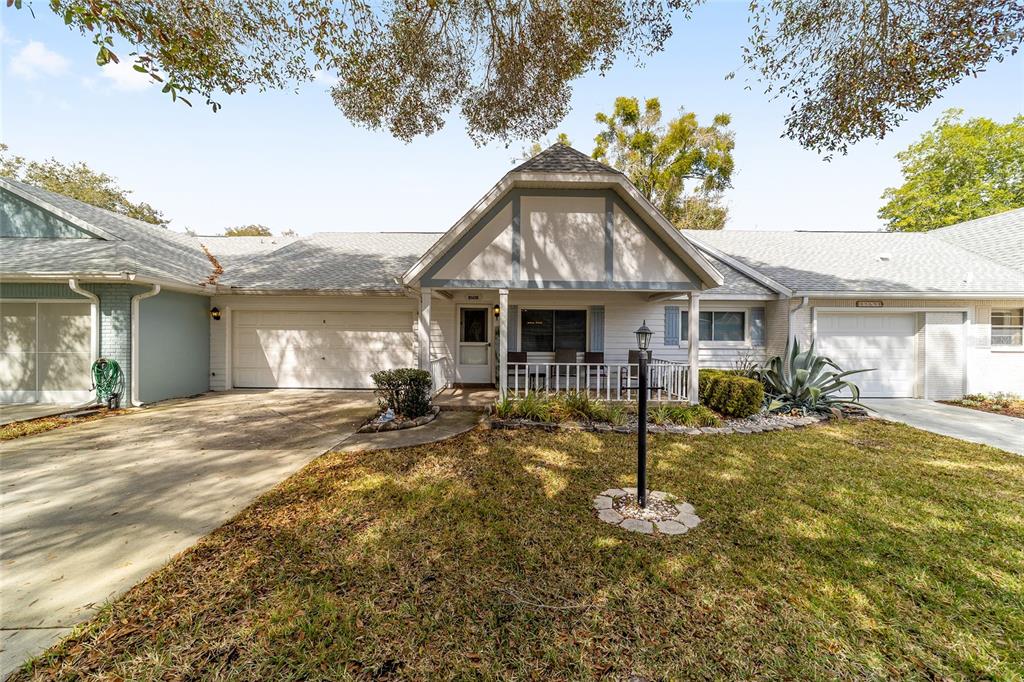 A single-story house with a front porch, two garage doors, and a grassy yard — 8569 SW 92ND LANE UNIT E, OCALA, FL