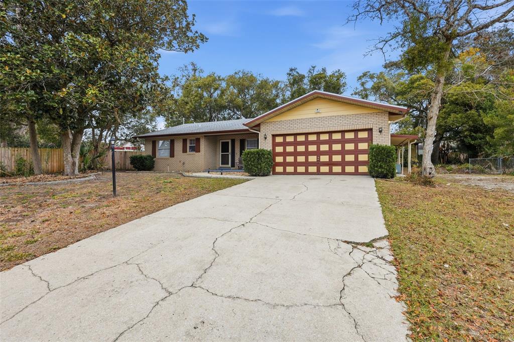 A single-story brick house with a two-car garage and a cracked concrete driveway — 244 ANGELES ROAD, DEBARY, FL