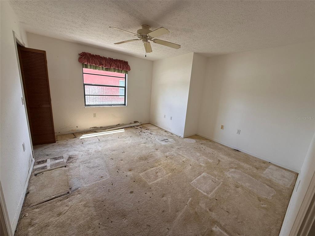 An empty bedroom with a ceiling fan, a window with a valance, and damaged carpeting — 8548 CYPRESS LAKES BOULEVARD, NEW PORT RICHEY, FL